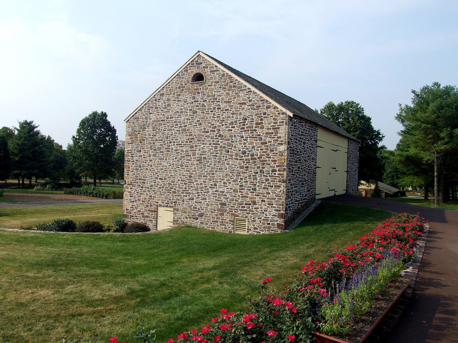 The stone Bank Barn behind its rose beds and estate lawn